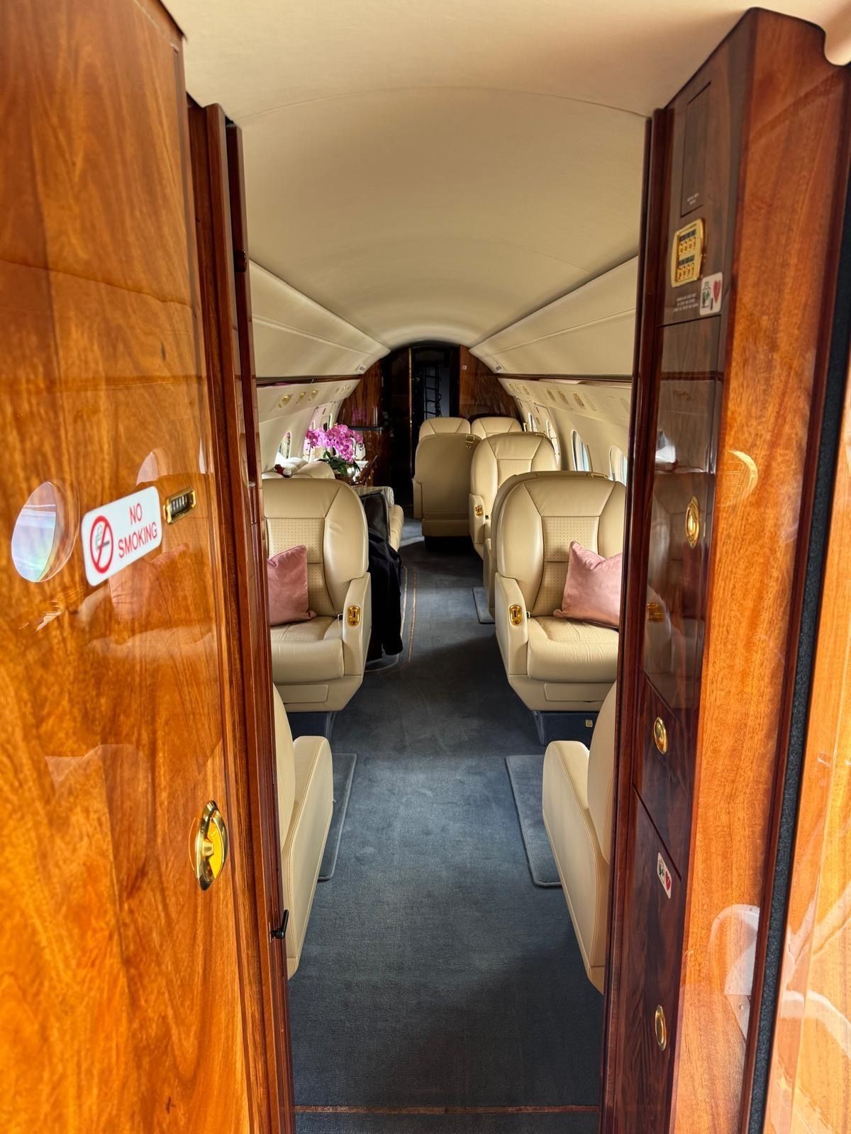 Open door of a business jet, looking into a cream leather cabin with orchids on the credenza