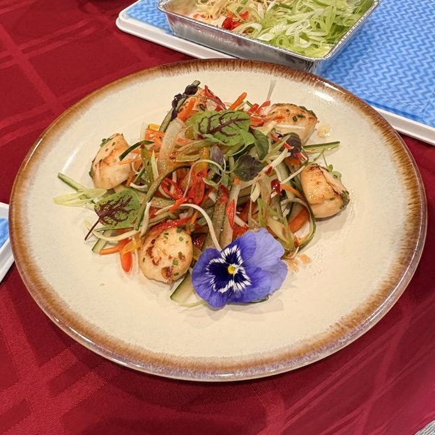 Seared scallops on a julienne salad with an edible flower